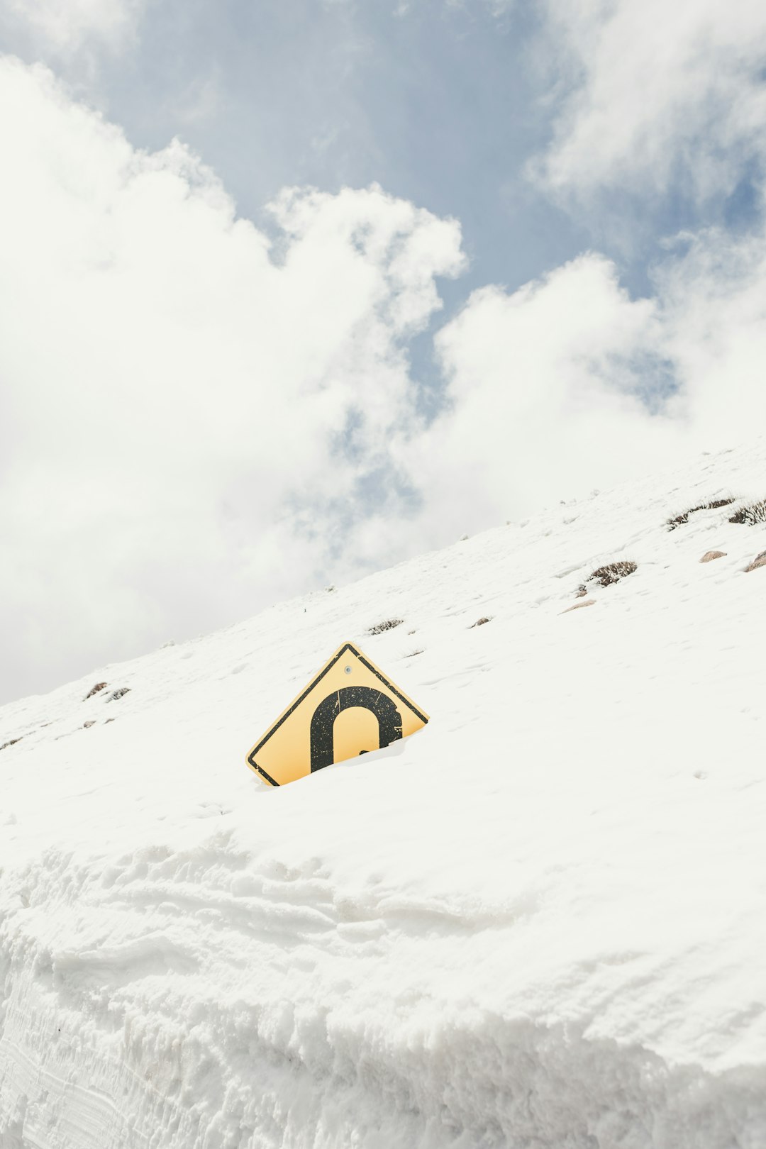 diamond-shaped yellow and blue signage covered by snow