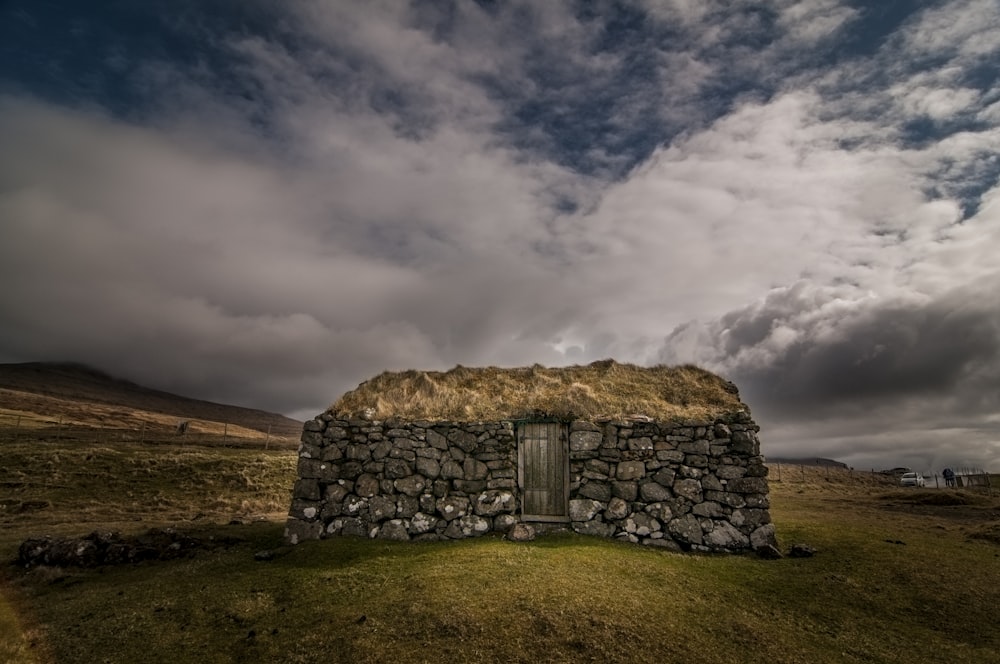 stone house on hill under blue cloudy sky