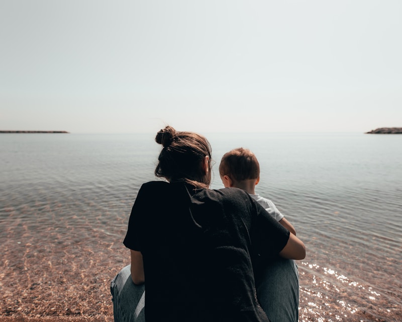 person holding child while facing sea