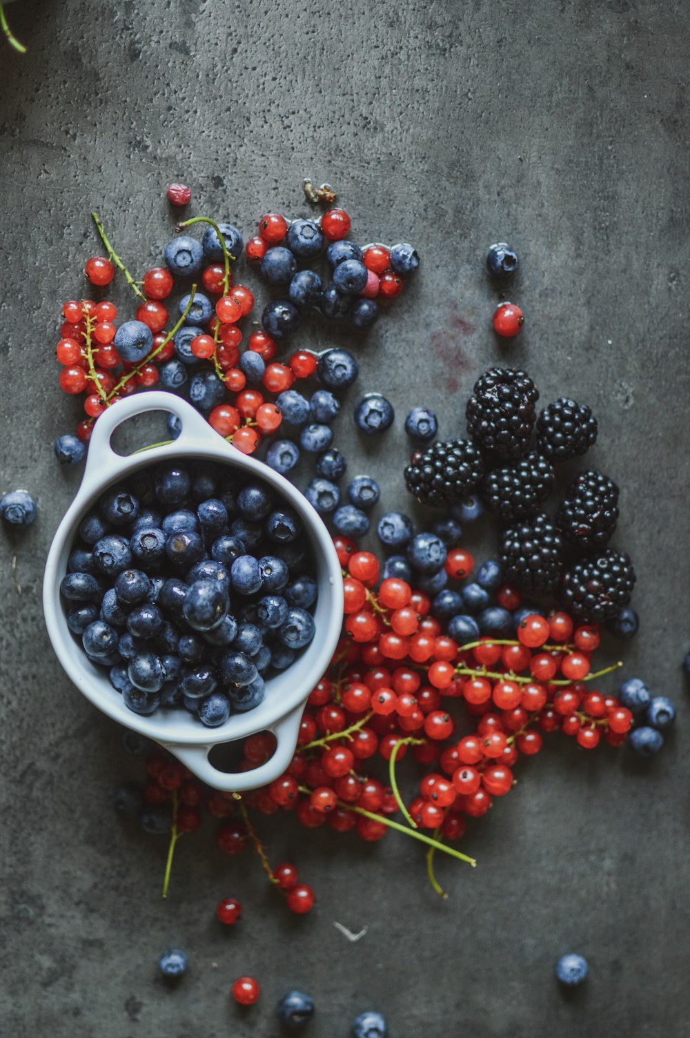 round red and blue berries beside bowl