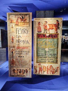 Two vintage posters advertising the Festas da Agonia event in Viana do Castelo, dated August 1912. The posters feature traditional illustrations, including people in cultural attire, a horse, and a cow. The left poster highlights activities such as horse competitions, parades, and serenades. The right poster emphasizes livestock contests and fireworks, with vibrant illustrations surrounding the text.