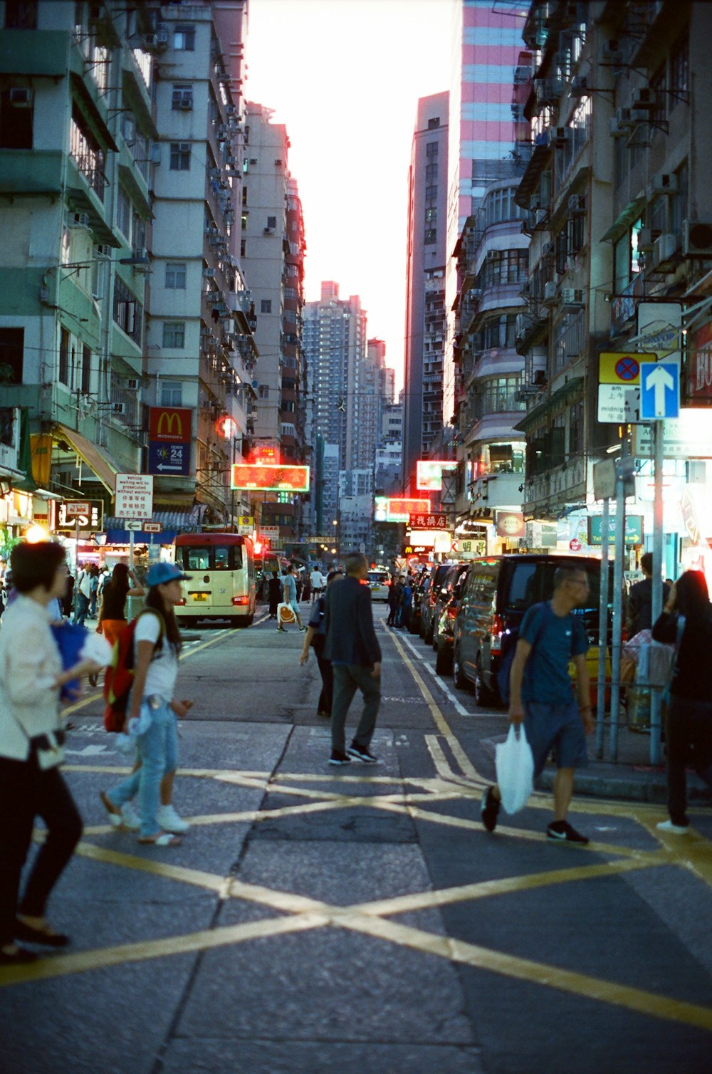 people walking on pathway near buildings and different vehicles on road during night time