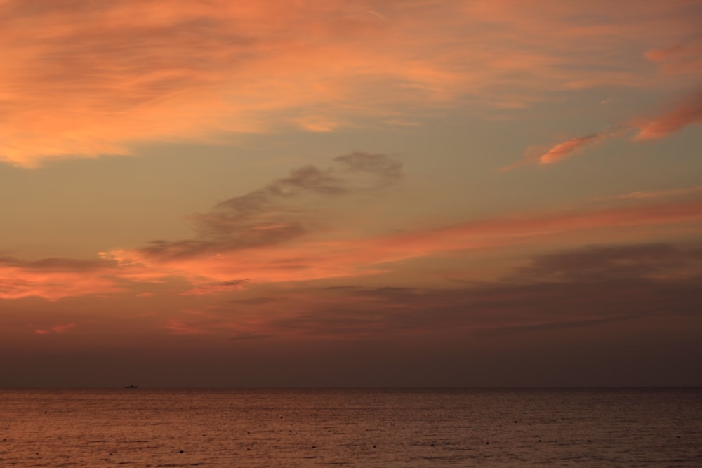 a sunset over a body of water with a boat in the distance