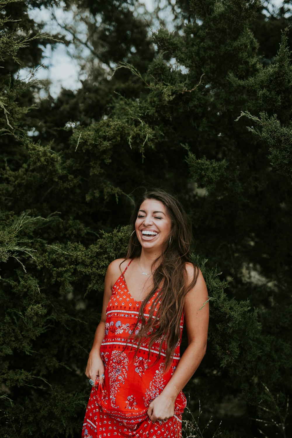 woman laughing while standing near tree