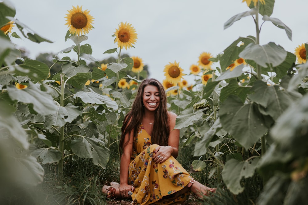 smiling woman sitting on sunflower field