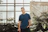 man in blue crew-neck top standing near plants