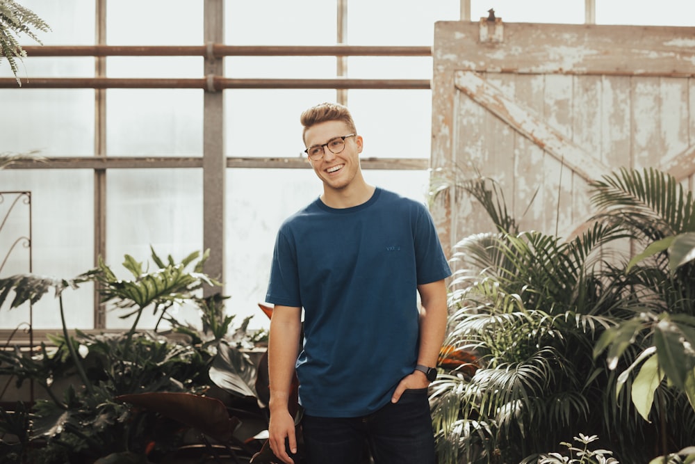 man in blue crew-neck top standing near plants