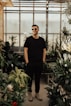 man in black crew-neck top standing near plants