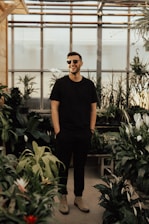 man in black crew-neck top standing near plants