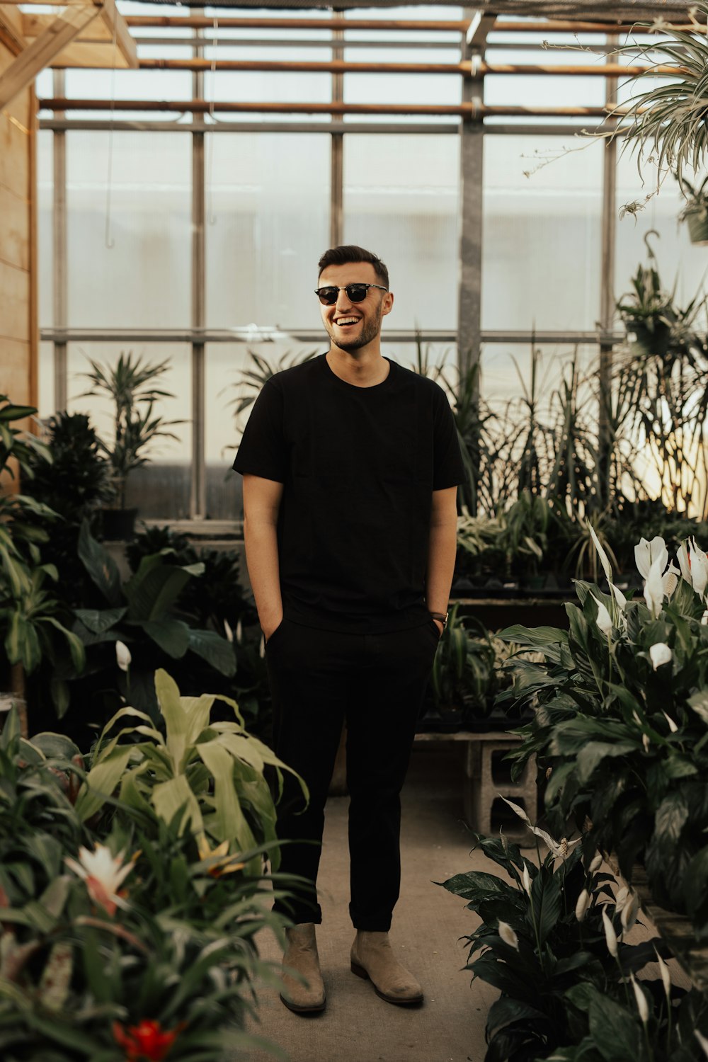 man in black crew-neck top standing near plants