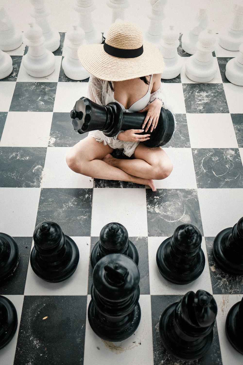 woman sitting on floor holding black chess piece
