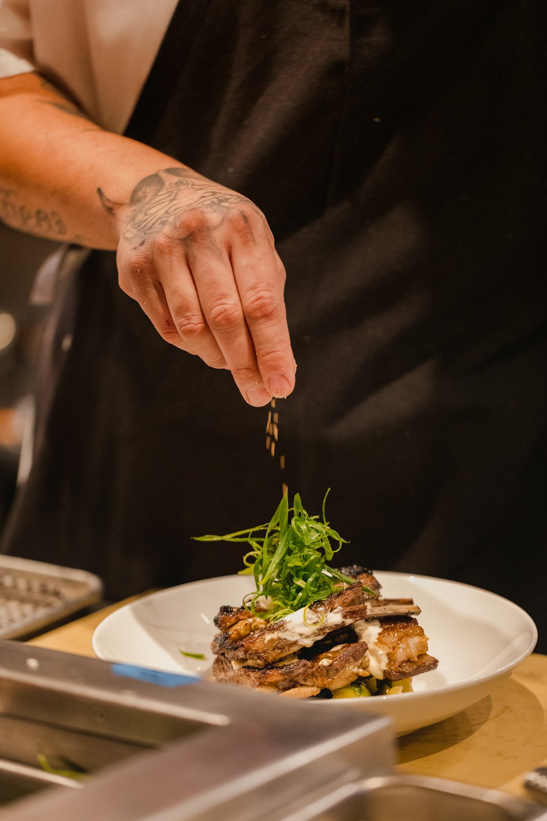 chef pouring seasoning on beef stake on plate