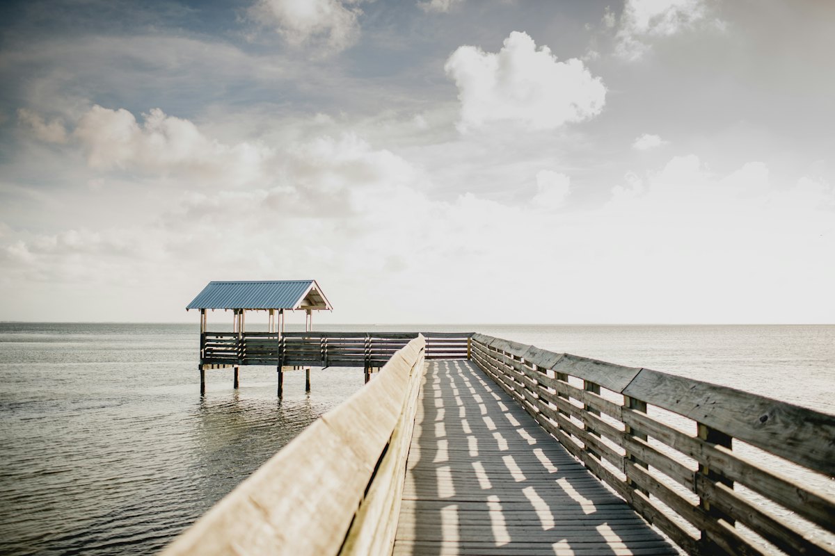 A wooden pier and covered platform over calm bay water