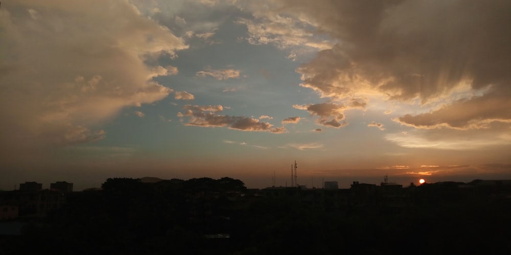 the sun is setting behind a cloud filled sky