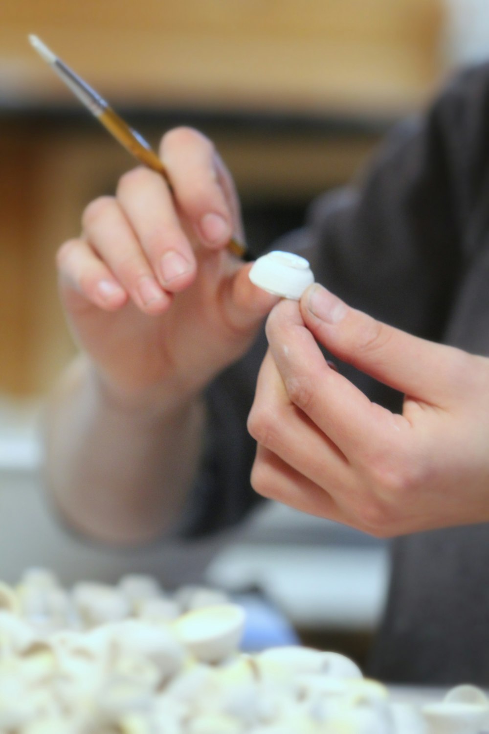 person holding small white bowl and paint brush