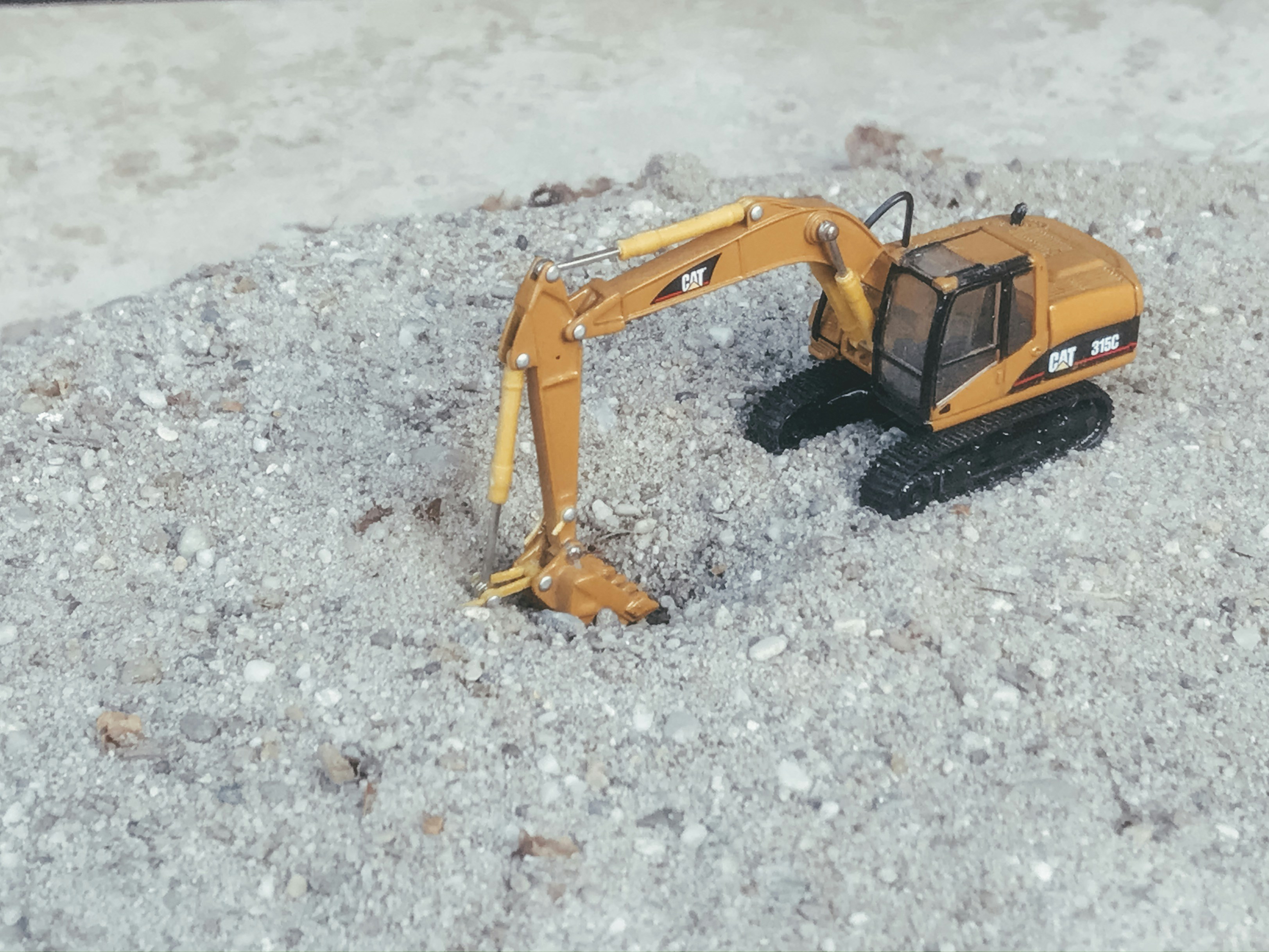yellow excavator toy on sand\