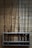 Several fishing rods are neatly organized on a wooden rack mounted against a wooden wall. The rods vary in color and style, some with red or black accents, alongside wood and metallic finishes.