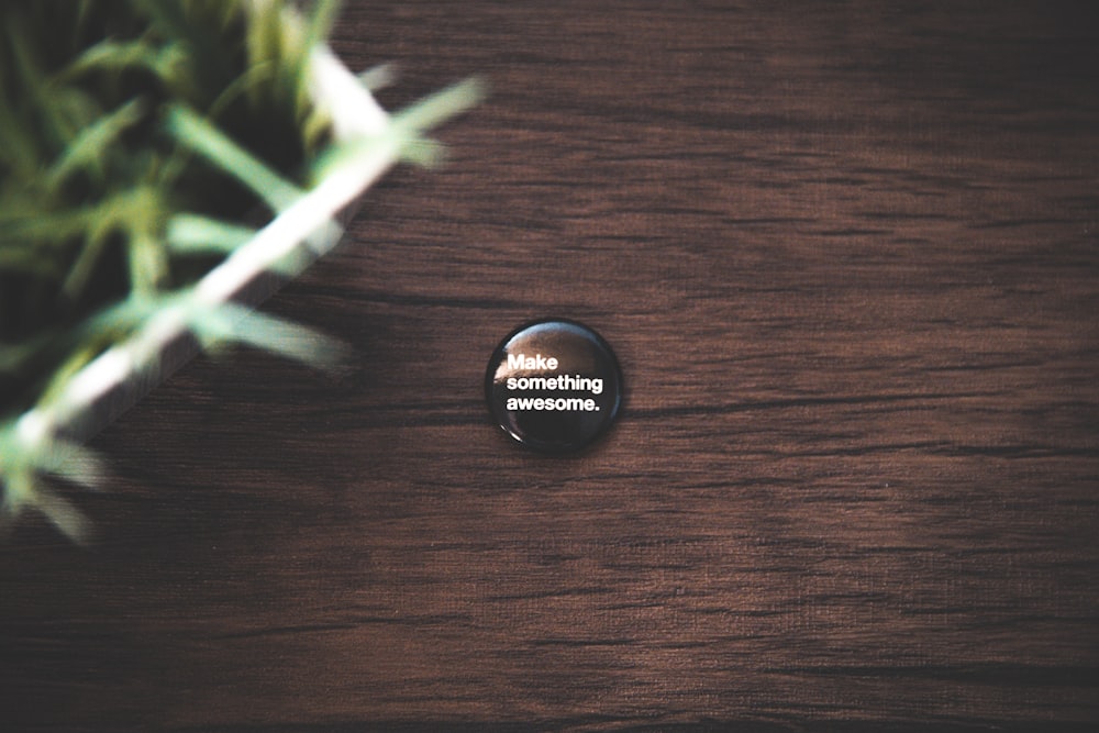 round black button pin on brown wooden surface