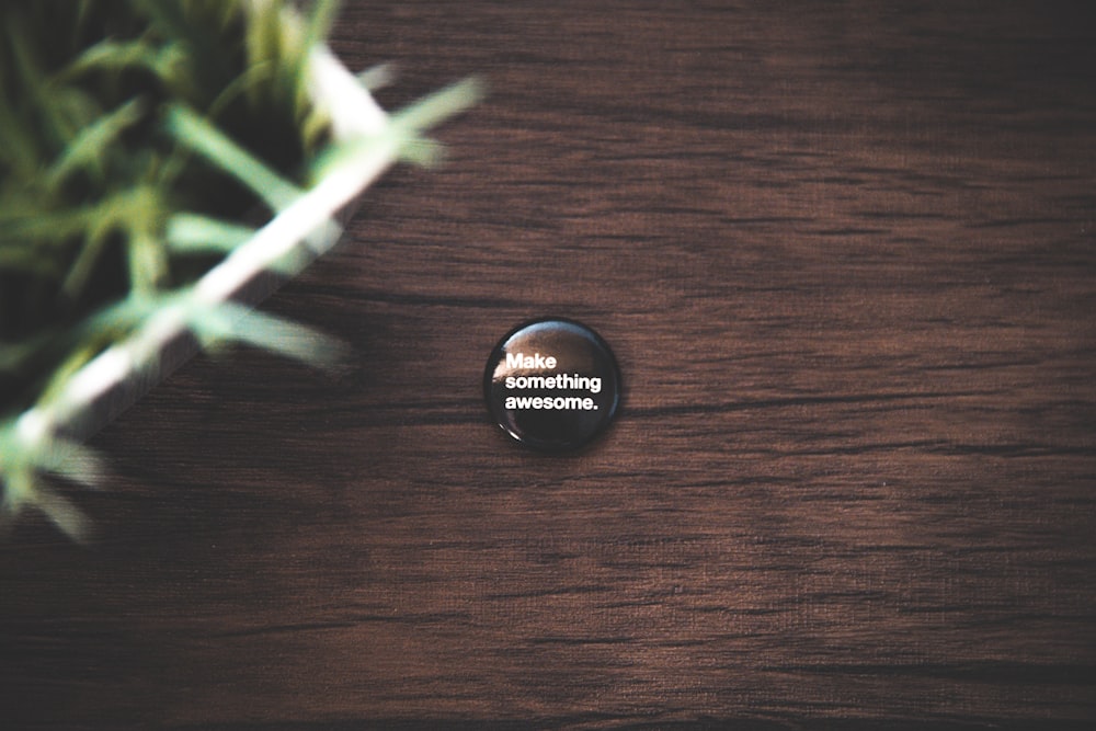 alfiler de botón negro redondo sobre superficie de madera marrón