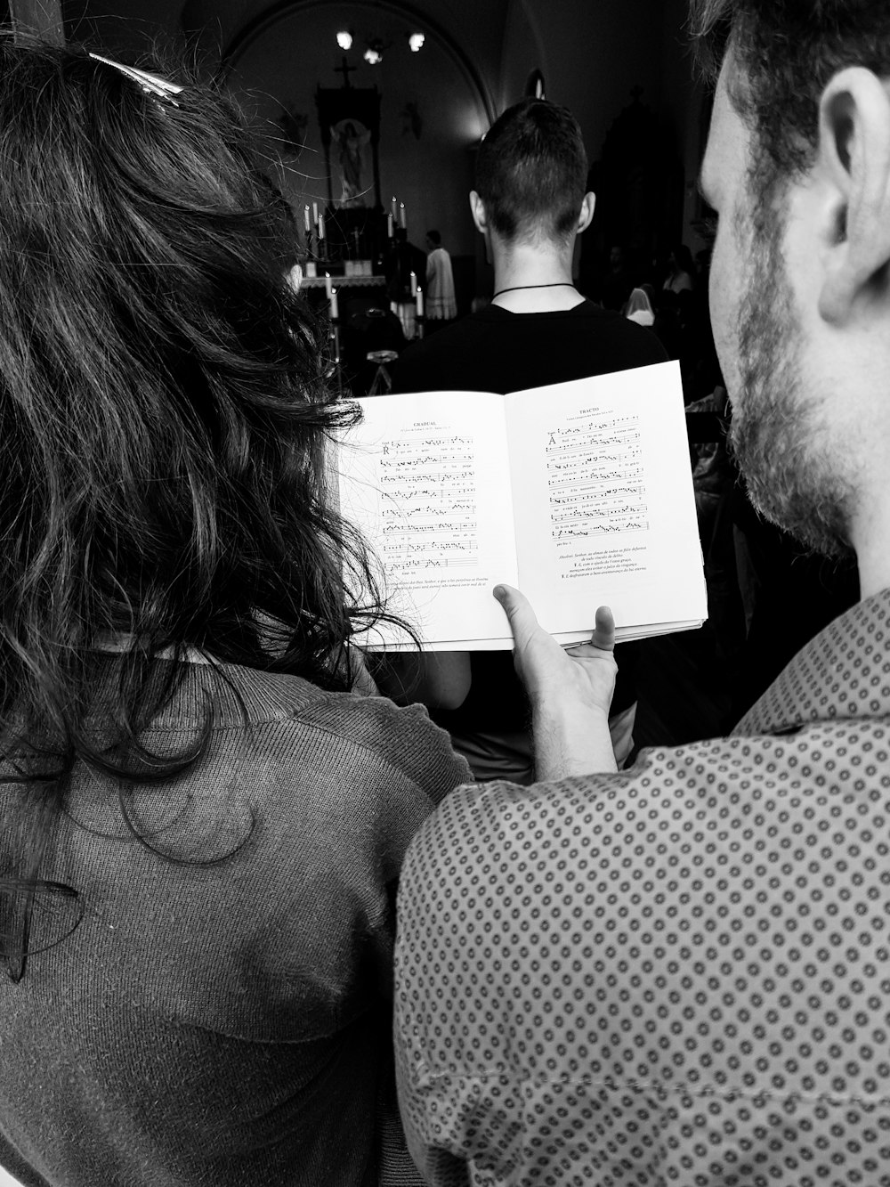 grayscale photo of man holding book