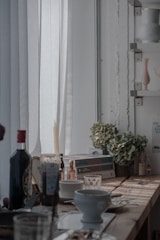 A cozy kitchen scene with warm cream and oatmeal tones, featuring a rustic wooden table set with a bowl of fresh herbs and an open devotional book.