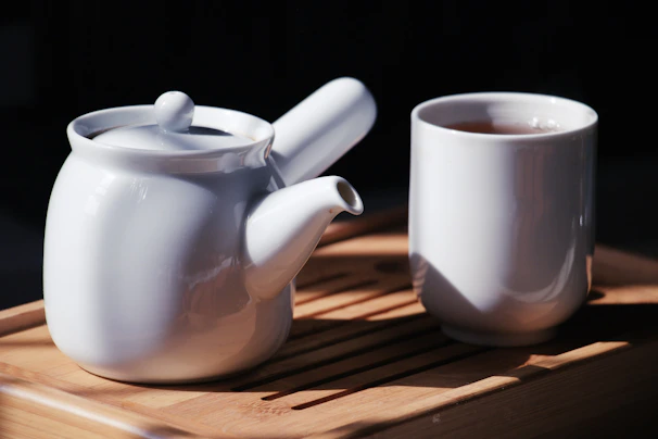 A warm-toned ceramic teapot with steam rising, placed beside a window with soft morning light.