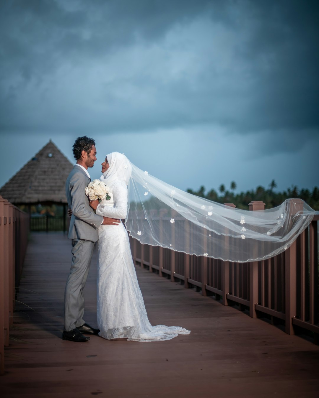 man in gray suit standing beside woman in white wedding gown at brown wooden dock bridge