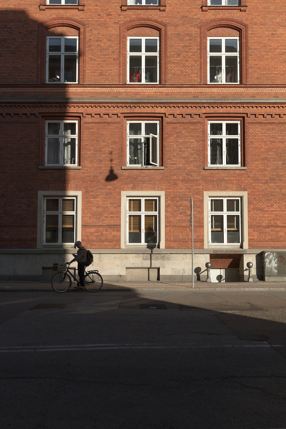person riding road bike beside brown brick building during daytime