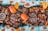A vibrant and colorful seafood feast is displayed, featuring large crabs, shrimp, and mussels surrounded by rice and garnished with sliced mangoes and watermelon. Various grilled meats and a dish of dipping sauce are arranged on wooden platters, creating an inviting and appetizing arrangement.