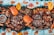 A vibrant and colorful seafood feast is displayed, featuring large crabs, shrimp, and mussels surrounded by rice and garnished with sliced mangoes and watermelon. Various grilled meats and a dish of dipping sauce are arranged on wooden platters, creating an inviting and appetizing arrangement.