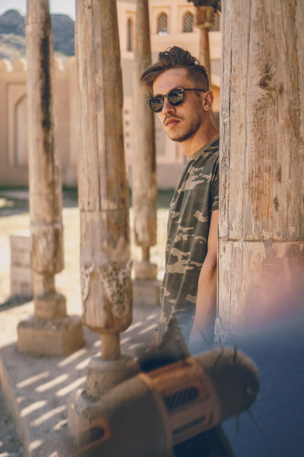 man leaning against a wooden post