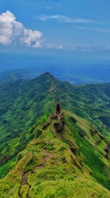 aerial photography of road viewing mountain under blue and white sky during daytime