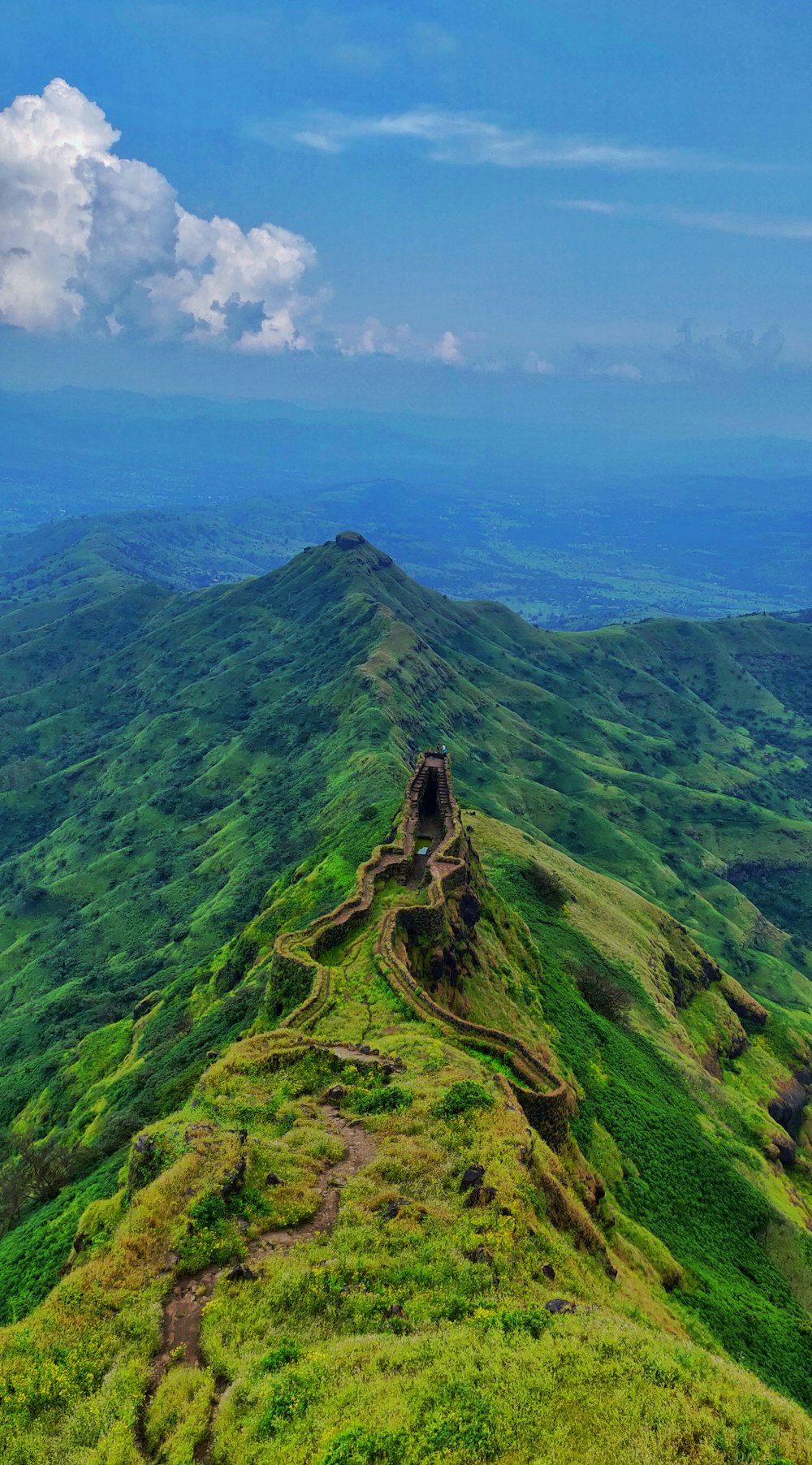 aerial photography of road viewing mountain under blue and white sky during daytime