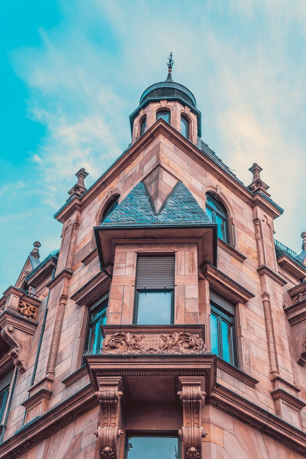 fotografia de baixo ângulo do edifício histórico marrom sob o céu azul e branco durante o dia