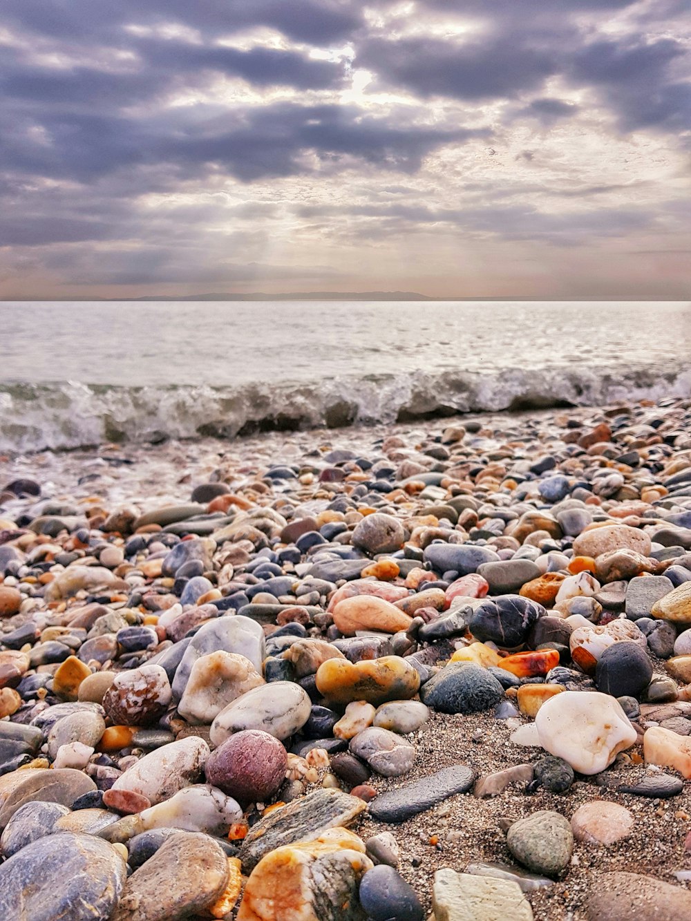 pebbles on seashore under cloudy sky