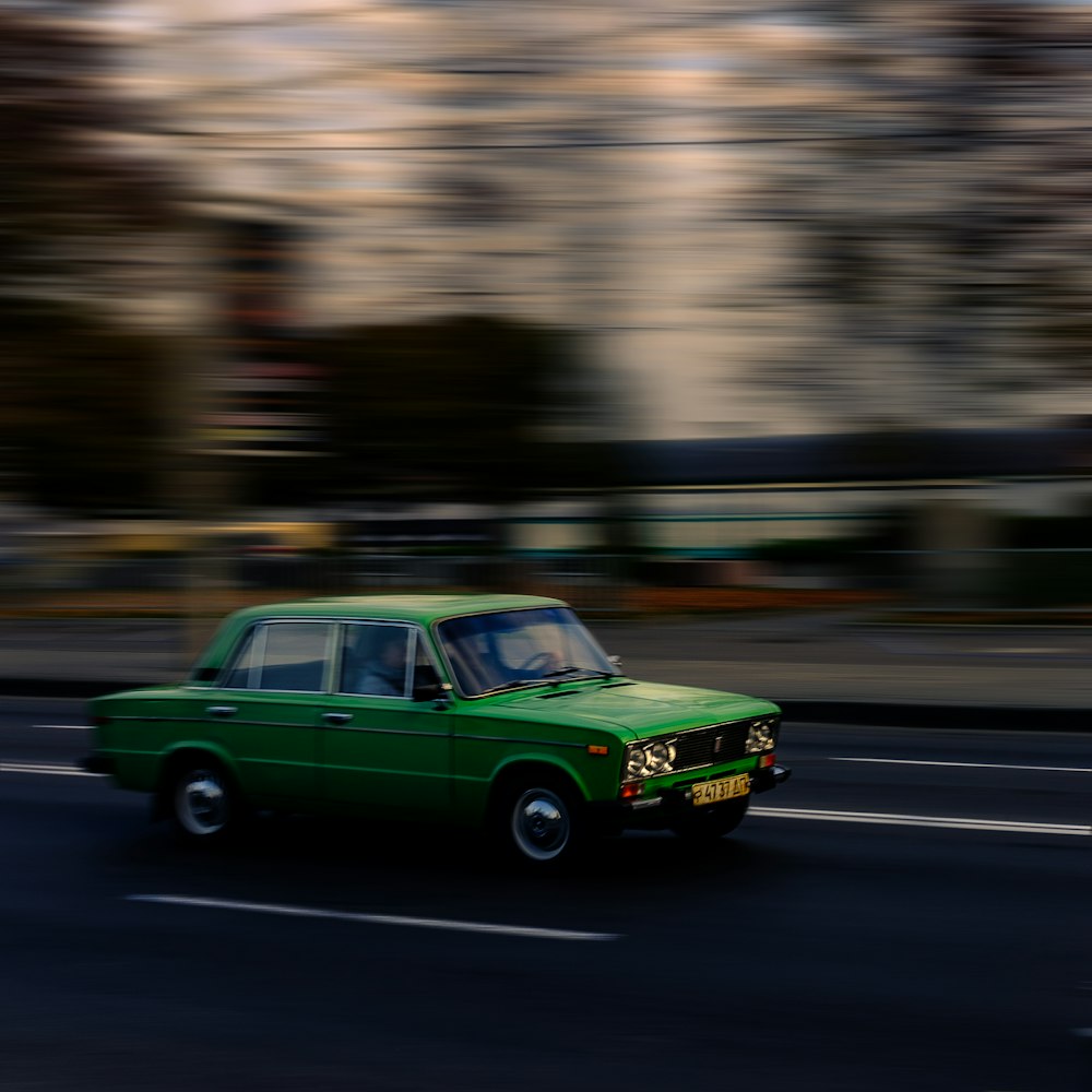 green sedan traveling on road