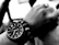 Close-up of a stylish man wearing a sleek black and silver bucce bracelet, highlighting minimalist design.