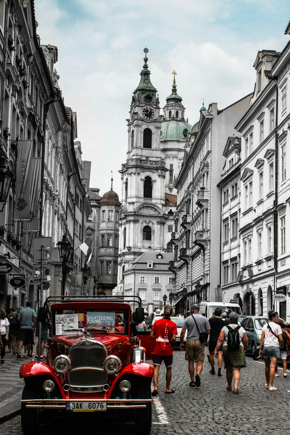 selective photography of people walking on road near vintage car