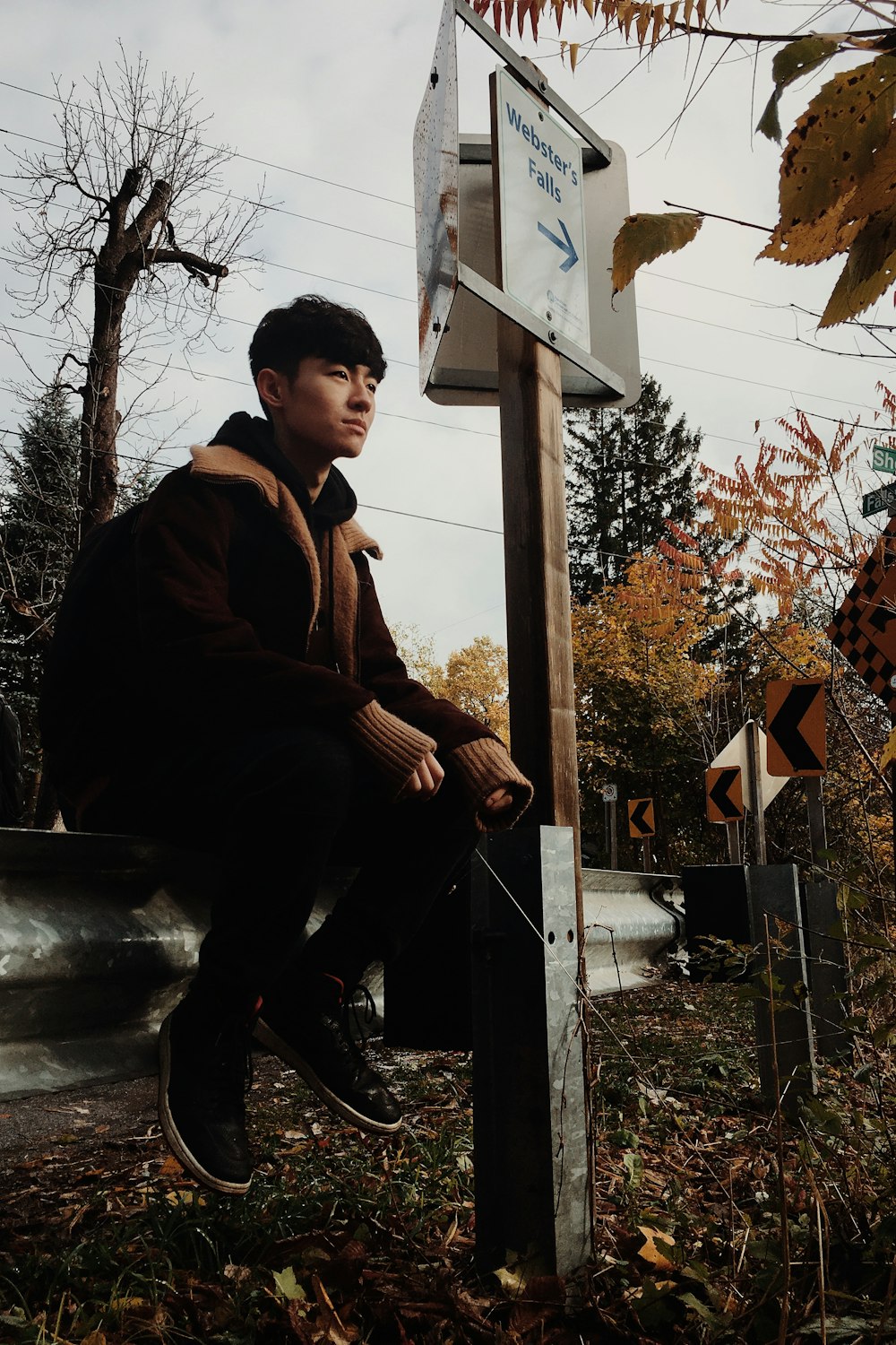 man sitting on road gutter during daytime