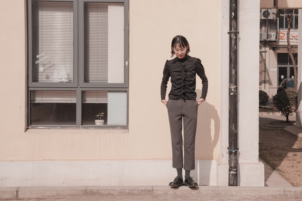 a woman standing on a sidewalk in front of a building