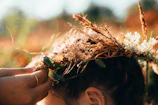 Close-up of hands weaving a ceremonial wreath from wild herbs.