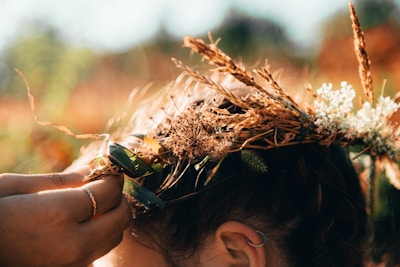 Close-up of hands weaving a crown of wildflowers and nightshade berries.