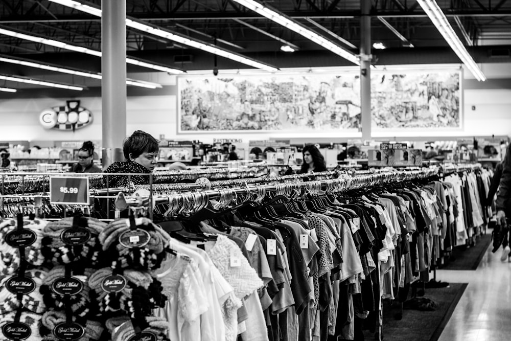 fotografia em tons de cinza de pessoas dentro de uma loja de roupas