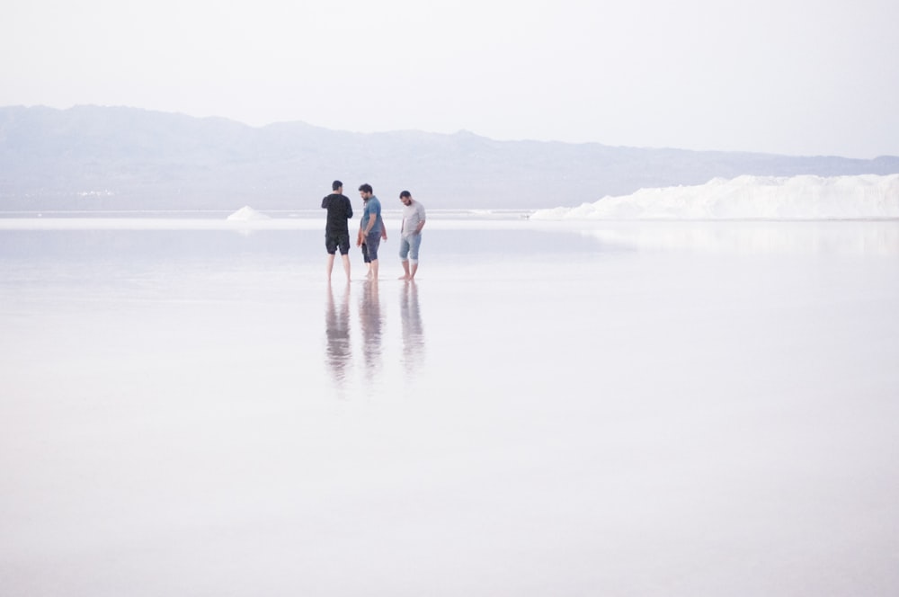 three men standing on shore