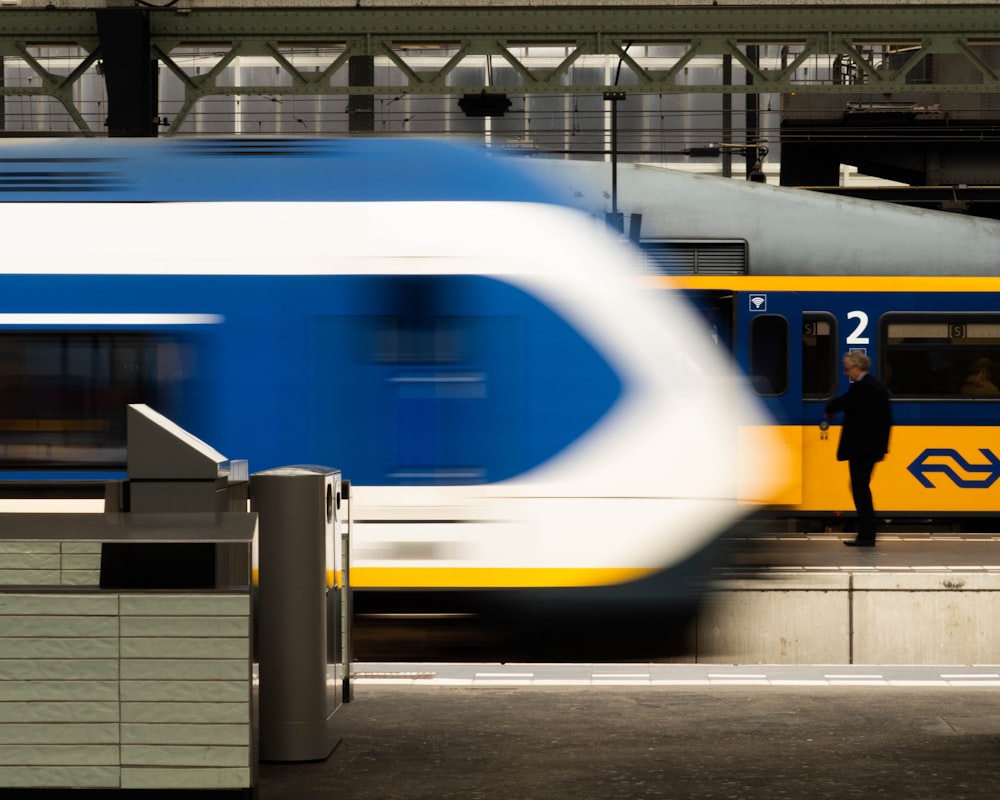 Persona in piedi vicino al treno giallo e blu