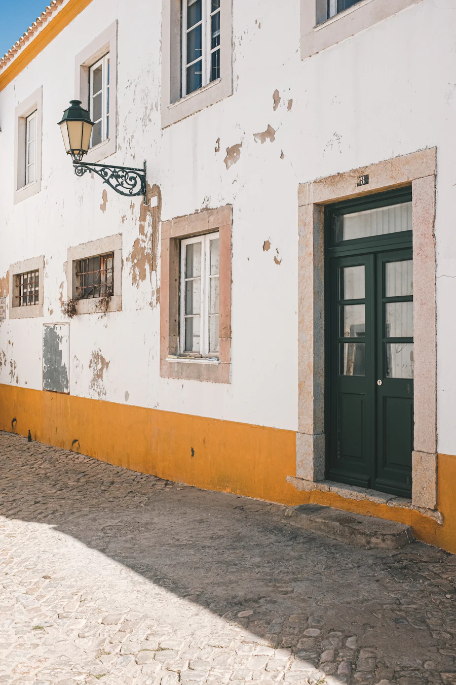 Fachada branca com barra amarela e porta verde