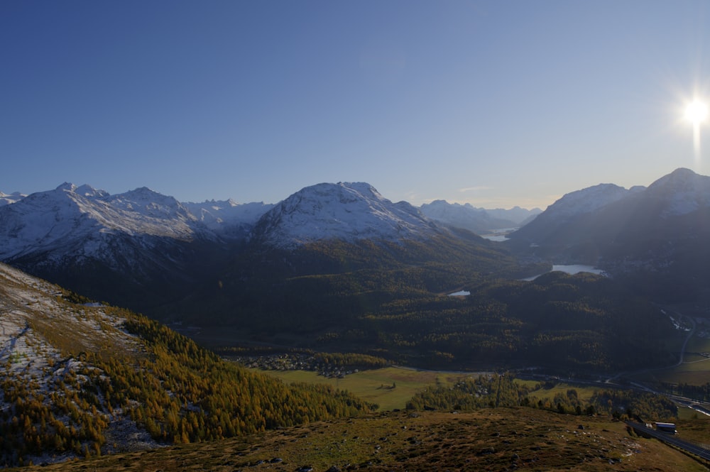 green valley surrounded by snowy mountains