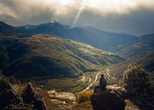 man sitting on rock with view of green hills with vegetation during daytime in Pyrénées-Orientales France