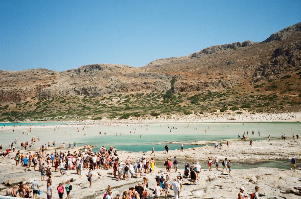 crowd of people standing and lying on beach during daytime