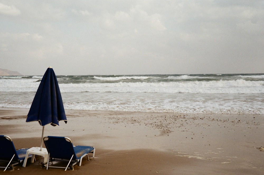낮 동안 해변에 파란색과 흰색 접이식 의자